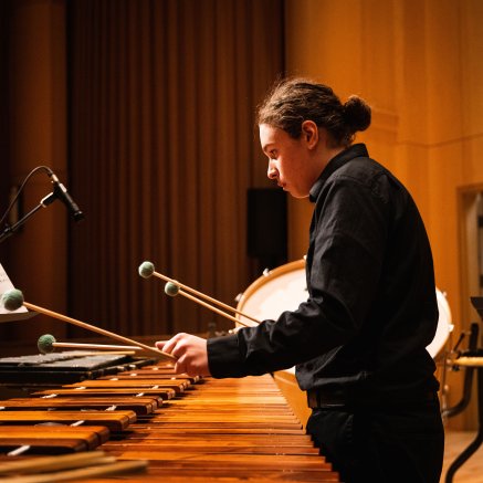 Chris playing marimba with other percussion instruments in the background