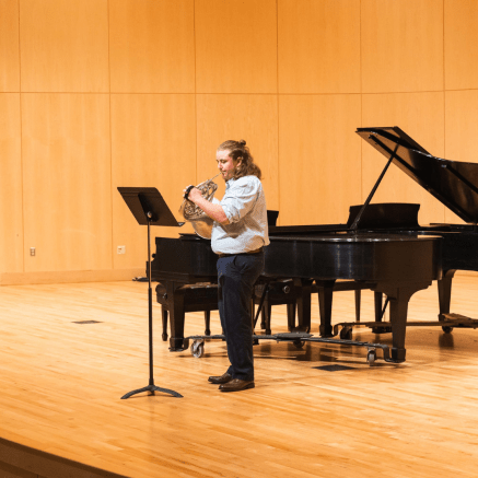 man playing a french horn on a stage