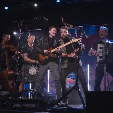 5 male musicians playing various instruments on a stage