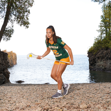 female lacrosse player standing on a beach